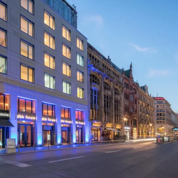 Beleuchtete Straße mit modernen und historischen Gebäuden bei Sonnenuntergang