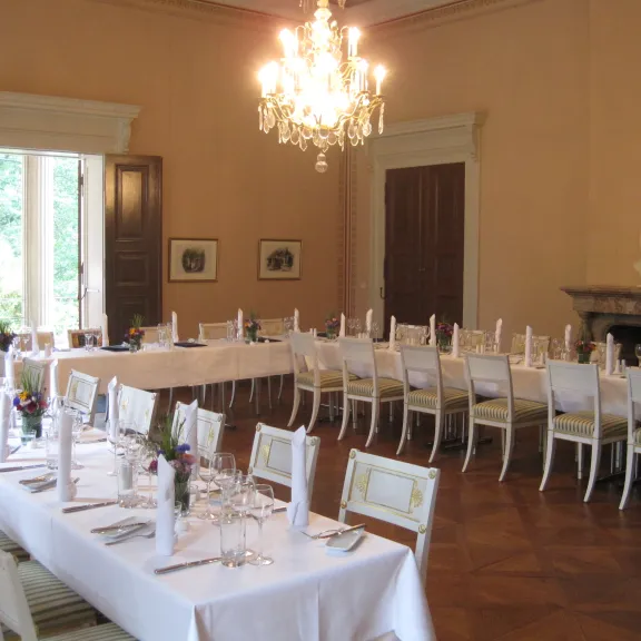 Eleganter Speisesaal mit weiß gedeckten Tafeln und Kronleuchter.