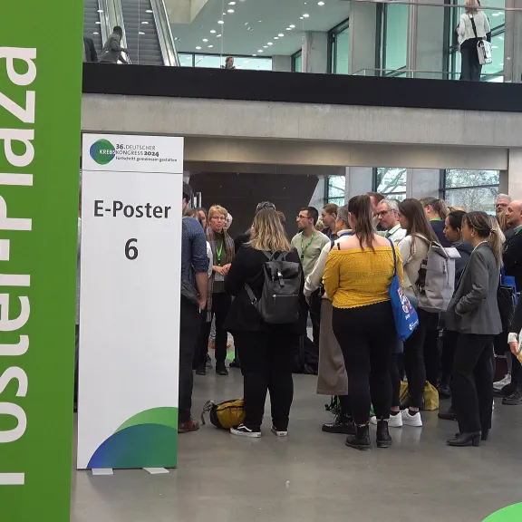 Teilnehmende versammeln sich auf dem DKK 2024 in der Poster-Plaza vor einer ePoster-Station, um wissenschaftliche Beiträge zu diskutieren.