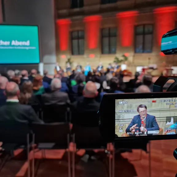 Blick durch die Kameralinse auf eine Podiumsdiskussion beim politischen Abend des DKK 2024; im Fokus der ehemalige Gesundheitsminister Prof. Karl Lauterbach.
