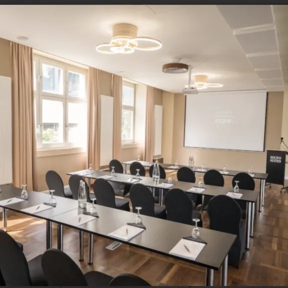 Heller Seminarraum mit Tischen, Stühlen, Beamer 