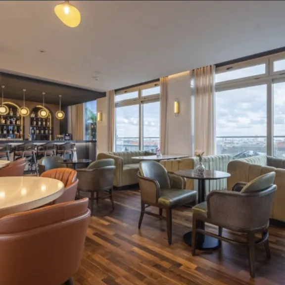 Modernes Café mit großen Fenstern, gemütlichen Sesseln und Blick auf die Stadt.