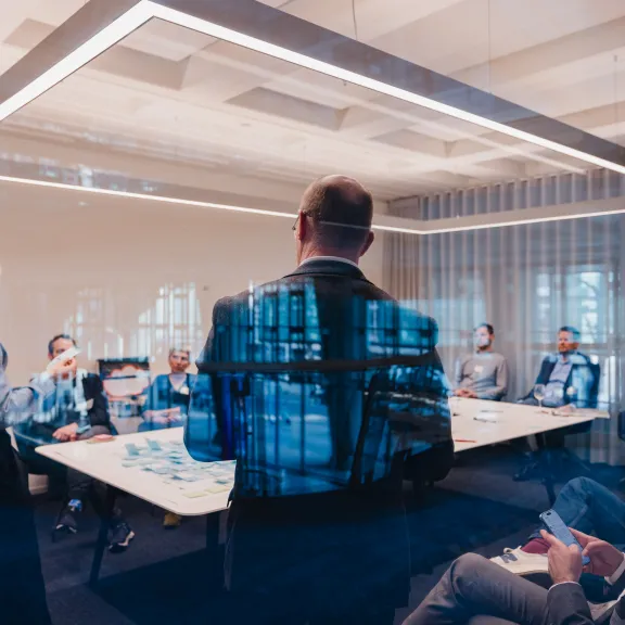 Menschen in einem modernen Konferenzraum bei einer Besprechung um einen großen Tisch.
