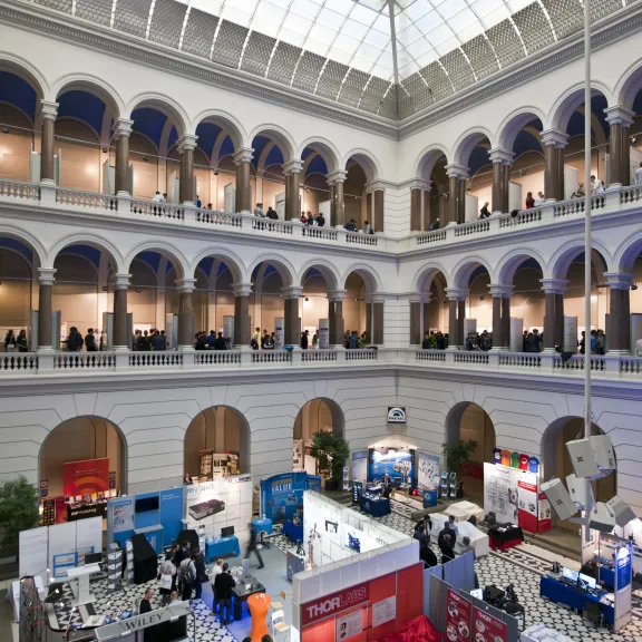 Große Messe in einem hellen, historischen Innenhof mit vielen Ständen und Menschen.
