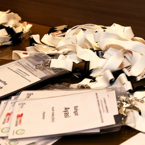 Namensschilder mit weißen Schlüsselbändern liegen auf einem Tisch.