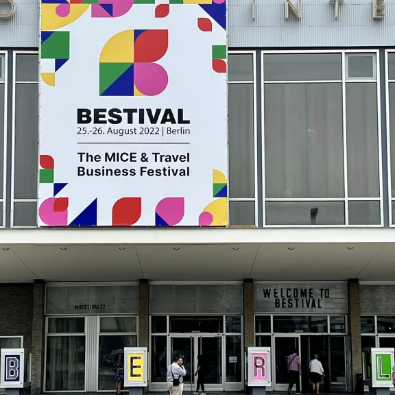 Großes, buntes Festivalbanner hängt über dem Eingang eines modernen Gebäudes.