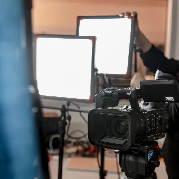 Eine Person stellt eine Beleuchtung neben einer Kamera auf.