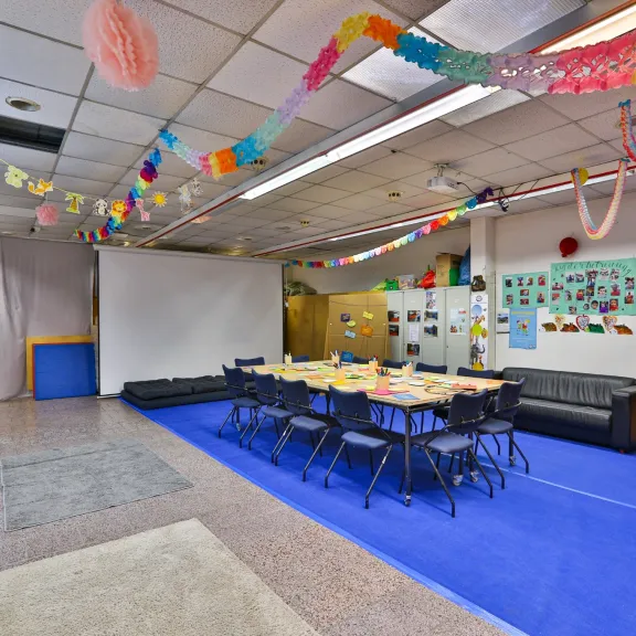 Bunte Kita mit Tischgruppe, Girlanden und Spielen an den Wänden