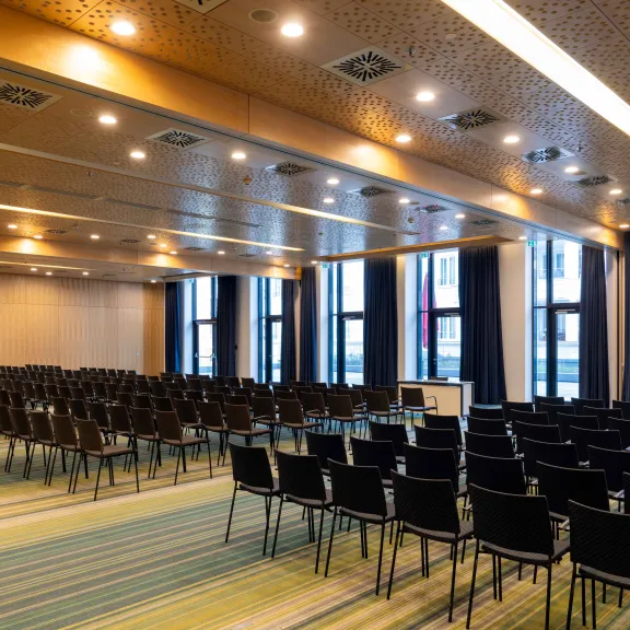 Leerer Konferenzraum mit vielen schwarzen Stühlen und großen Fenstern.