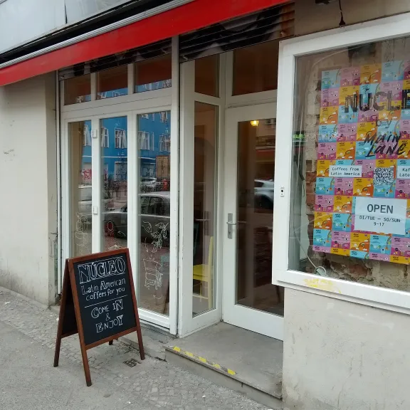 Café-Eingang mit bunter Fensterdekoration und Tafel vor der Tür.