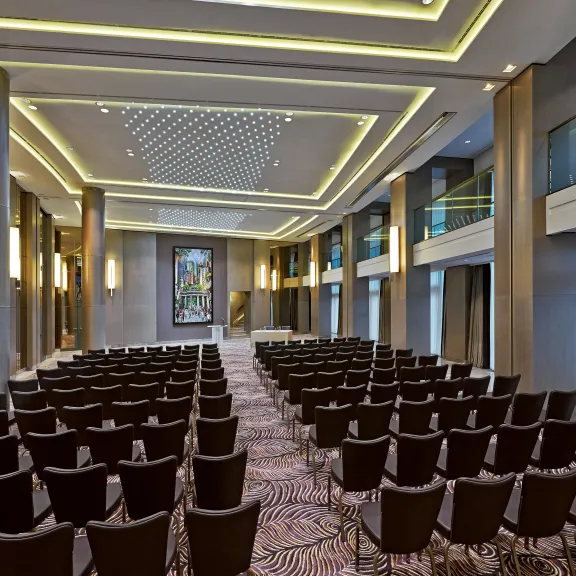 Modernes Hotelzimmer mit großem Bett, Schreibtisch, Sessel und großen Fenstern.