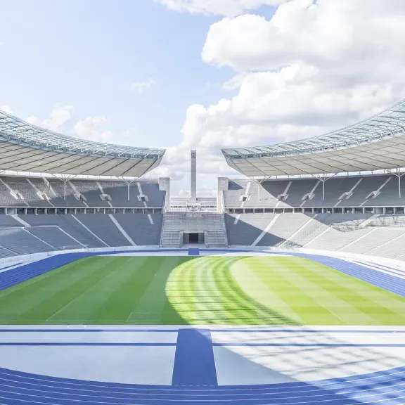 Innenraum des Olympiastadions Berlin mit Tribünen, blauer Laufbahn und grünem Fußballrasen