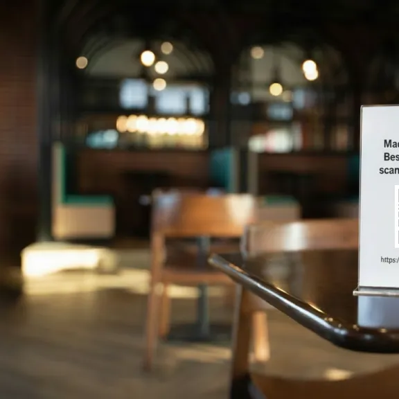 Tischaufsteller mit QR-Code, der Gäste einlädt, zu scannen und abzustimmen, um lokale Projekte zu unterstützen.