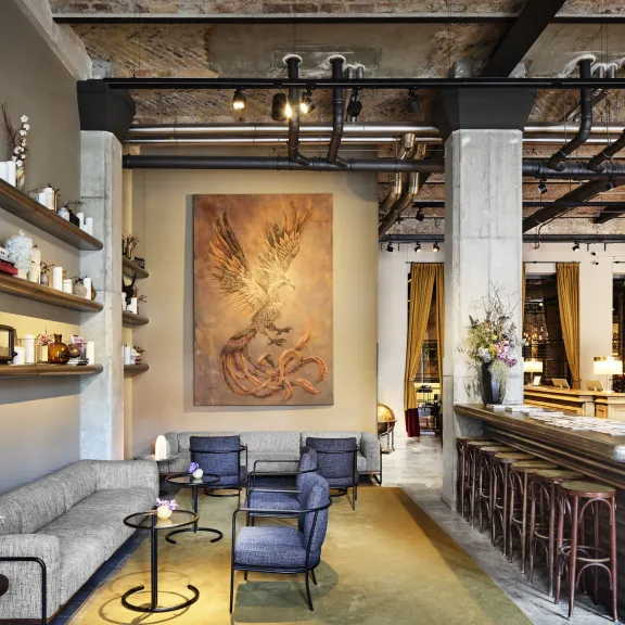 Modernes Hotellobby mit gemütlicher Sitzecke, großen Gemälden und stilvoller Bar.