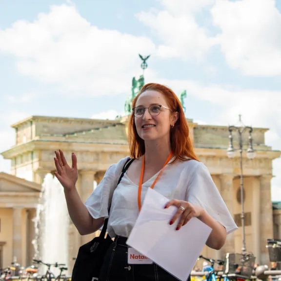 Reiseführerin Natalie leitet eine kleine Gruppe vor dem Brandenburger Tor, Berlin.