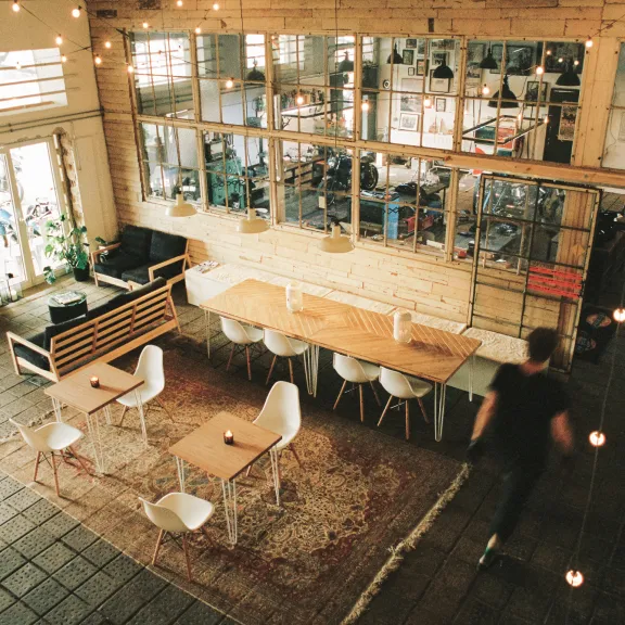 Heller, moderner Coworking-Space mit Holztischen, Stühlen und gemütlicher Beleuchtung.