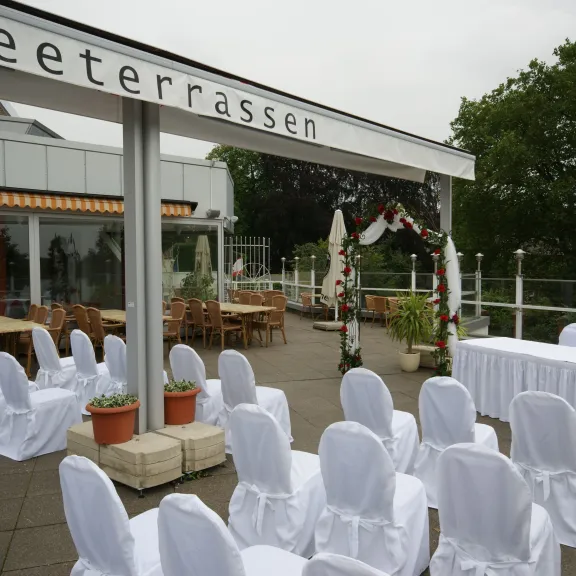 Terrasse der Tegeler Seeterrassen am Tegeler See mit Rosenbogen und festlich eingedeckter Hochzeitstafel