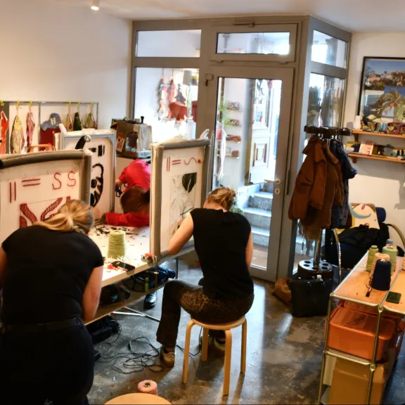 Teilnehmende gestalten bei einem Tufting-Workshop im Künstleratelier von Tufting Berlin eigene Teppichmotive an Tufting-Rahmen.