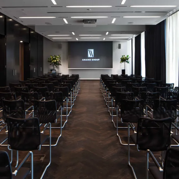 Leerer Konferenzraum mit Reihen schwarzer Stühle und Leinwand vorne