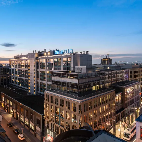Stadtansicht bei Sonnenuntergang mit modernen Gebäuden und beleuchteten Straßen.