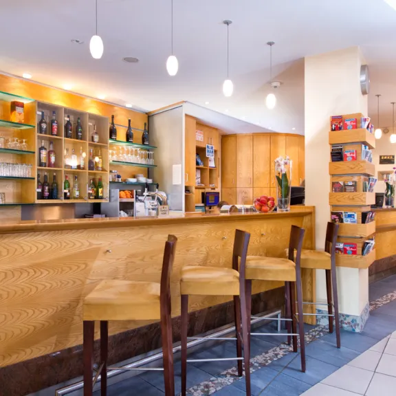 Leere moderne Bar mit Holztheke, Regalen und drei Barhockern.