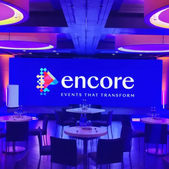 Modern eingerichteter Konferenzraum mit runden Tischen und lila-blauer Beleuchtung.