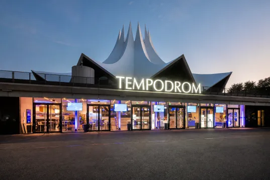 Eingangsbereich des Tempodroms bei Abenddämmerung mit beleuchteter Fassade