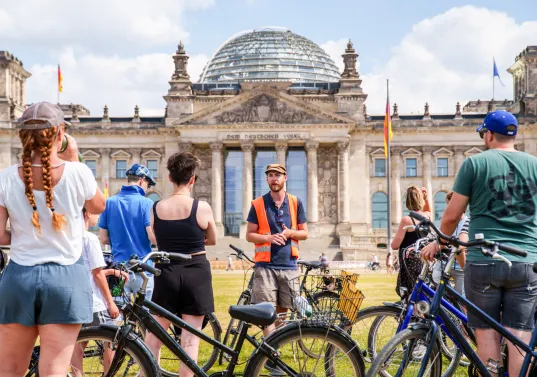 Eine Gruppe von Fahrrad-Nutzenden steht vor dem Berliner Reichtstag 
