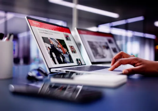 Person working on a laptop with presentation slides, modern office setting with technology and professional atmosphere.