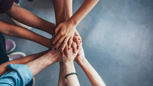 Close up top view of young people putting their hands together. Friends with stack of hands showing unity.
