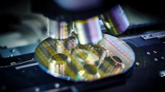 Microscope lenses magnify a silicon wafer with electronic circuits in a laboratory.