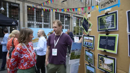 Exhibitor at a trade fair conversing with a lady