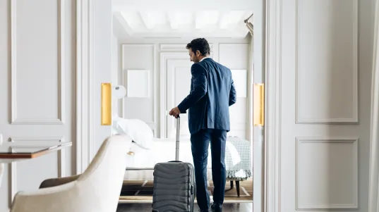 Businessman with trolley in hotel room 