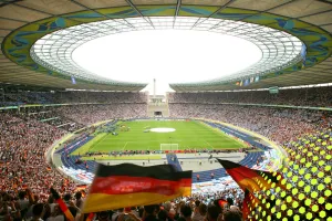 Voll besetztes Fußballstadion mit deutscher Flagge im Vordergrund