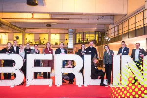 Mehrere Menschen stehen hinter großen weißen Buchstaben, die "BERLIN" buchstabieren.