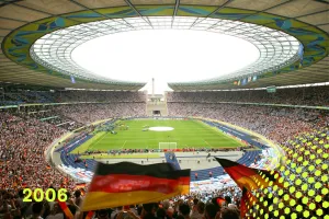 Fußballstadion mit vollen Tribünen und deutschen Fahnen, sonniges Wetter.