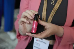 Close-up of a person holding a perfume bottle labelled ‘Neuro360’. 