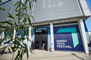 Entrance to the Green Tech Festival in Berlin with visitors and large blue banners on the building.