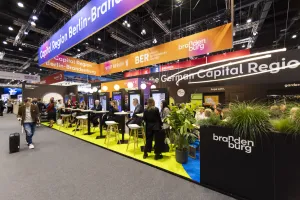 People networking at a colorful trade show booth for the German Capital Region.