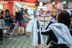 Visitors take photos in the futuristic entrance hall of the ICC Berlin with neon lights and retro design.