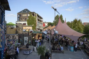 People sit and eat in a colourful Berlin courtyard with a tent roof and street art.