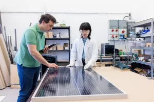 Male and female researchers working together to examine a solar panel in an agricultural lab workshop, showcasing their expe…