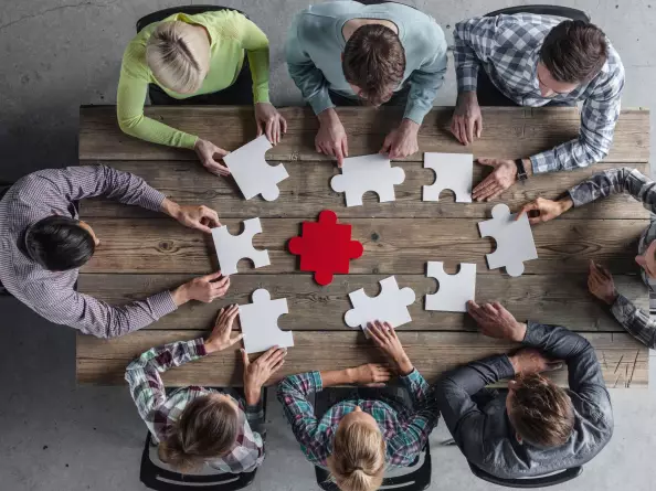 A team assembles puzzle pieces at a meeting