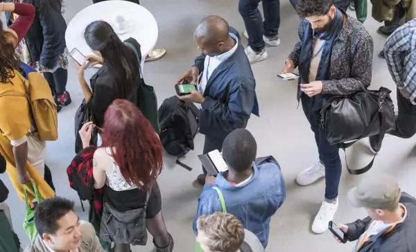 Businessleute benutzen ihr Smartphone bei einer Konferenz um Nachrichten zu erhalten