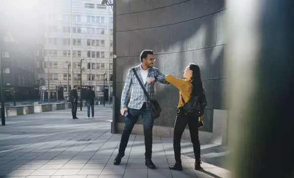 Mann und Frau begrüßen sich mit den Ellenbogen 