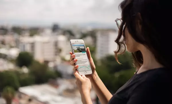 Frau schaut auf ihr Smartphone mit App "100 Jahre Bauhaus"