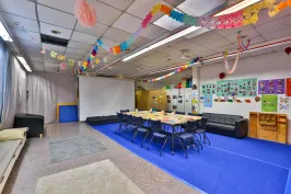 Bunte Kita mit Tischgruppe, Girlanden und Spielen an den Wänden