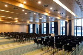 Leerer Konferenzraum mit vielen schwarzen Stühlen und großen Fenstern.