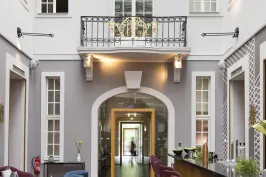 Heller, moderner Innenraum mit Bar, Barhockern und blauen Sesseln unter Glasdach.