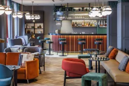 Moderne Hotelbar mit bunten Sesseln, Sofas und Barhockern, warme Beleuchtung